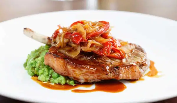 Chuleta de cerdo con guisantes triturados y salsa de pimiento rojo