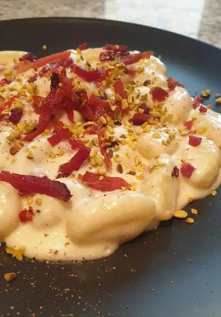 Potato gnocchi with Taleggio cream, speck, and chopped pistachios