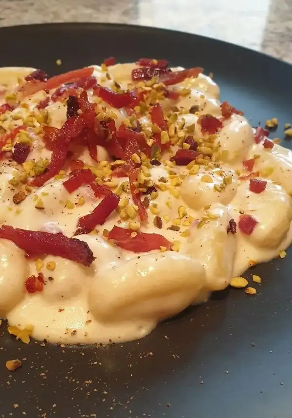 Ñoquis de patata con crema de Taleggio, speck y pistachos picados