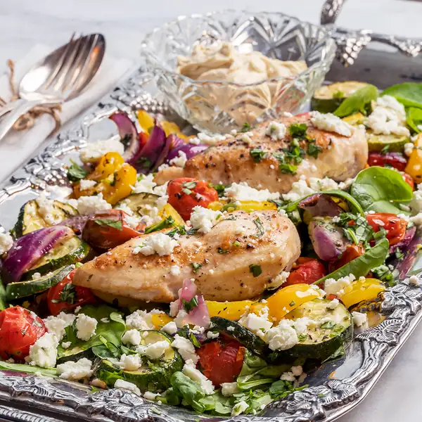 Mediterranean chicken on a plate with hummus