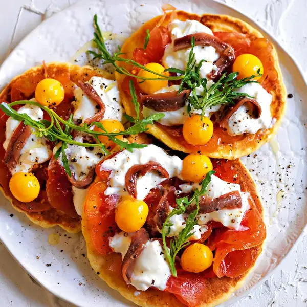 Chickpea pancakes with stracciatella, anchovies, and quail eggs