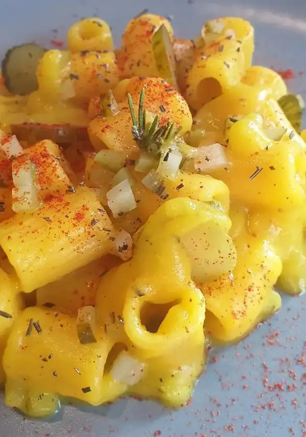 Mezzemaniche en crema de azafrán y romero con pepinillos agridulces y tomate en polvo
