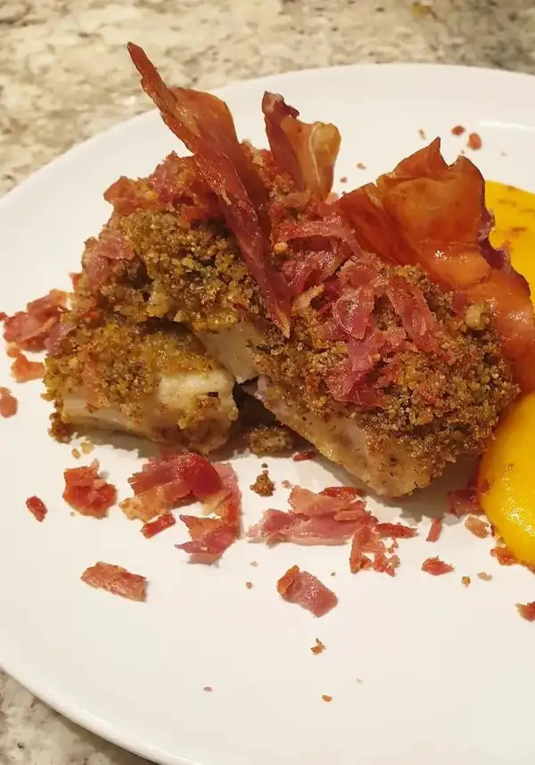 Cod fillets au gratin with almond flakes, saffron cream and crispy ham