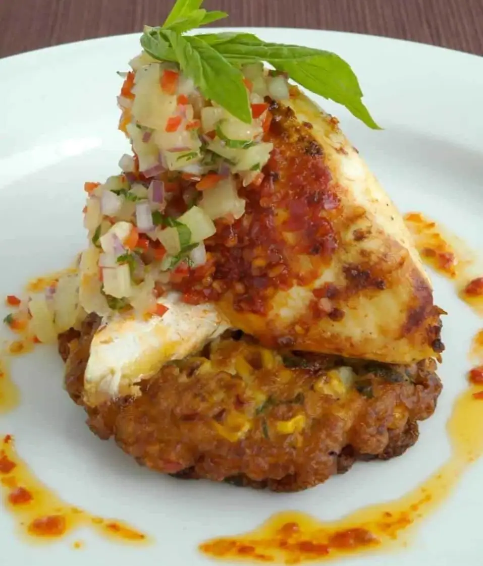 Pollo con harissa sobre buñuelos de maíz y cilantro con salsa de piña