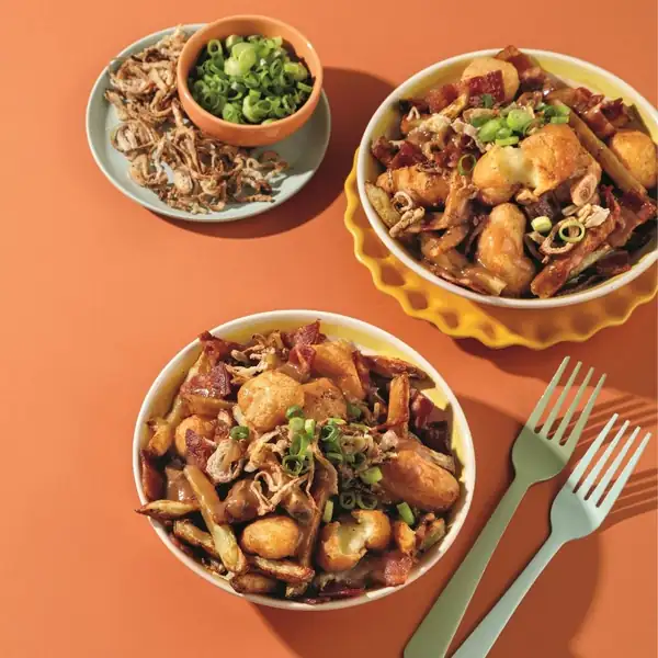 Deluxe poutine with crispy cheese curds, bacon, and fried shallots