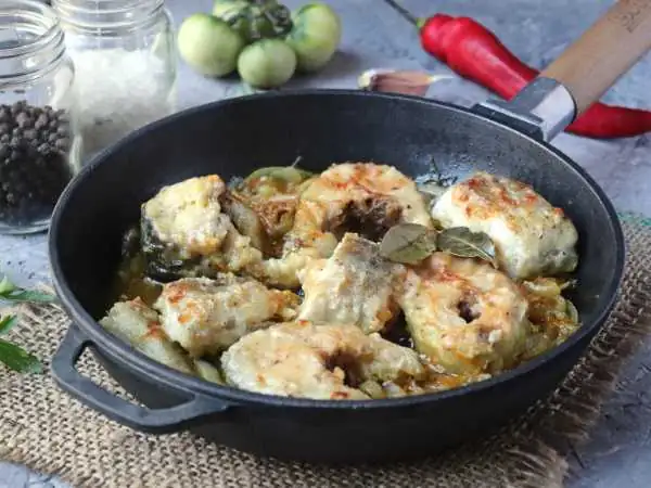 Pollock with onions and carrots in a frying pan