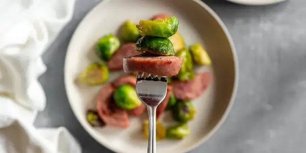 Salchichas y coles de Bruselas cocinadas en una sola bandeja