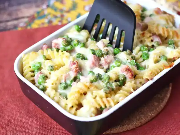 Baked pasta au gratin with ham, peas and mozzarella
