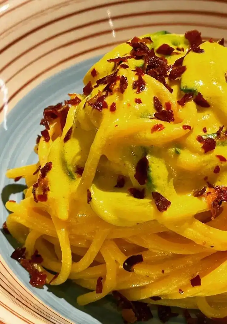 Spaghetti with saffron ricotta cream, courgettes and speck petals