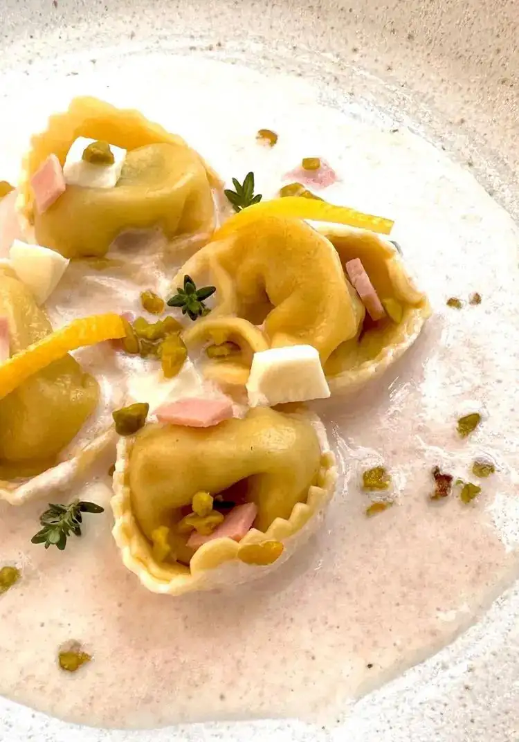Tortelloni de ricotta y espinacas con mortadela cremosa y mozzarella de búfala, pistachos picados y limón confitado