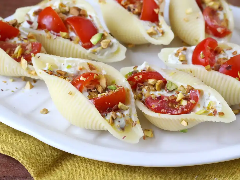 Conchiglioni filled with stracciatella, pistachios, cherry tomatoes and lemon