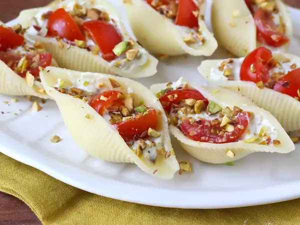 Conchiglioni filled with stracciatella, pistachios, cherry tomatoes and lemon