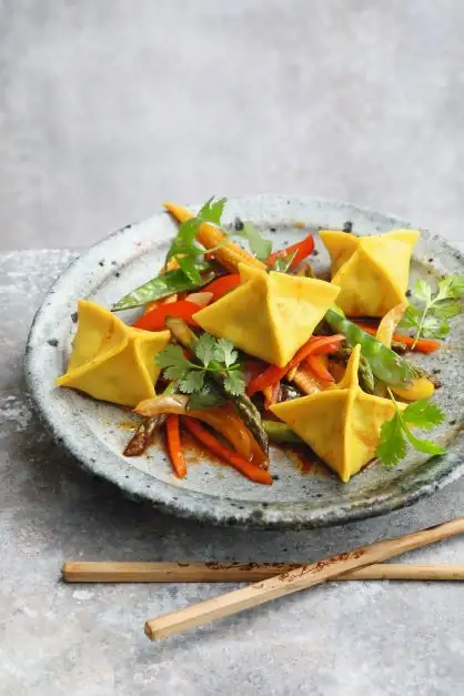 Steamed pasta pockets with shiitake mushroom and tofu filling and stir-fried vegetables