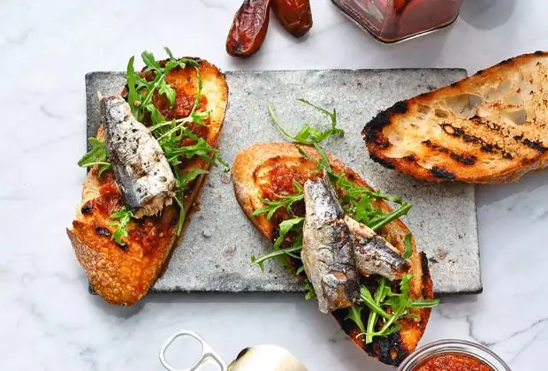 Sun-dried tomato and date pesto on baguette with arugula and oil-packed sardines